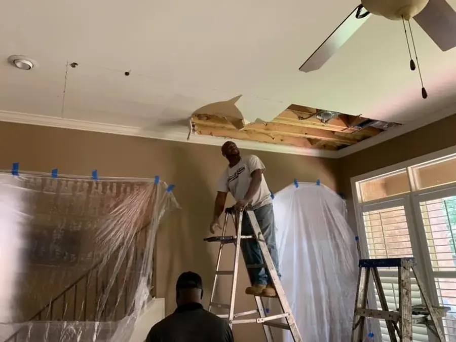 Technician repairing a water damaged ceiling after a leak in Addison